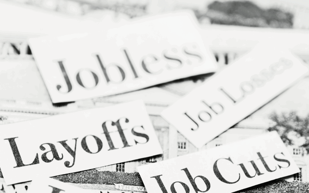 Newspaper clippings with headlines about layoffs, job cuts, and jobless rates, representing employee fears of AI-driven job displacement